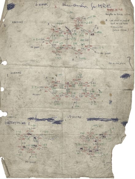 Yellowed paper page with tears in the lower left corner with diagrams and calculations written on it in pencil, and blue, red and green pen.
