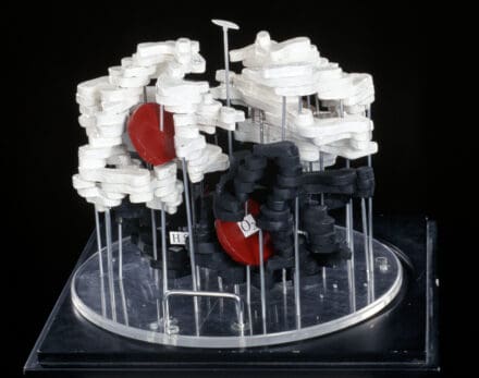 Scientific model constructed with wooden layers, coloured in white, black and red paint and held up with plastic rods.