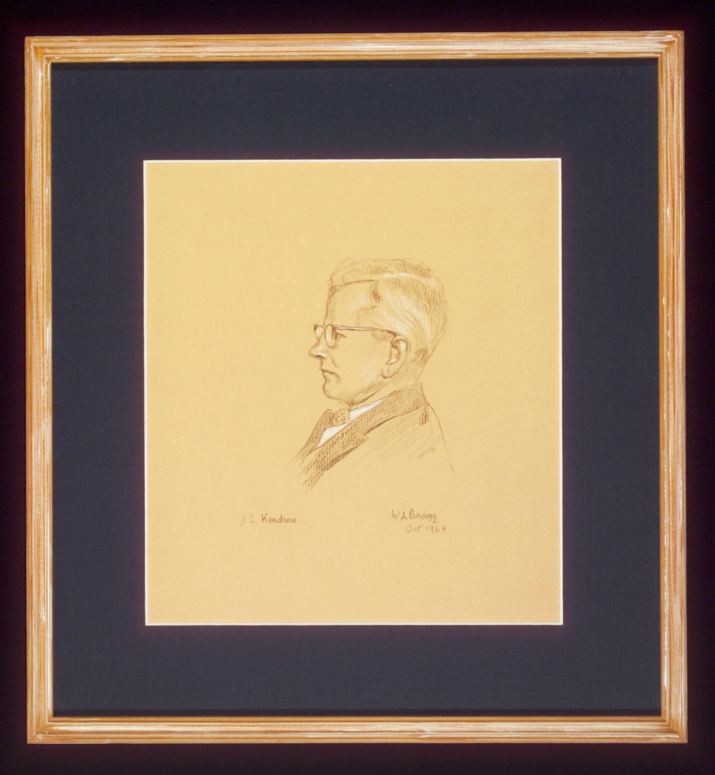 Yellowed paper with black and white sketch of a man in profile, in a wooden frame with a black mount