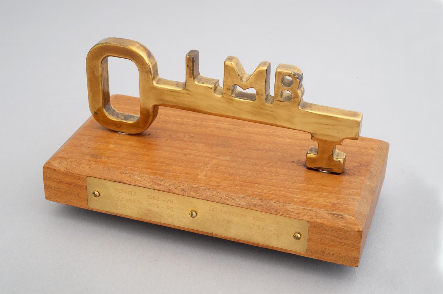 Wooden plaque with a metal key with letters LMB on the top