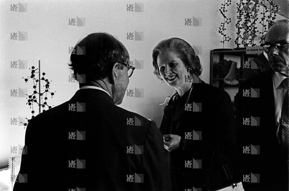 Margaret Thatcher with Max Perutz and a colleague in a laboratory with LMB logo watermark overlay.