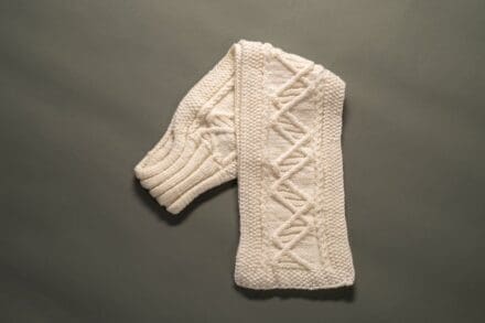 Cream white knitted rectangle, folded over itself to show the double-helical cable pattern