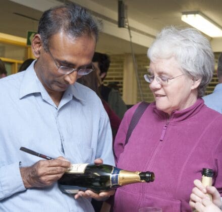 Venki Ramakrishnan signing a champagne bottle for Jenny Brightwell