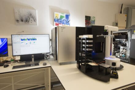 Sony flow cytometer and computer displaying colorful cell analysis data, with additional lab equipment and wall art in a bright room.