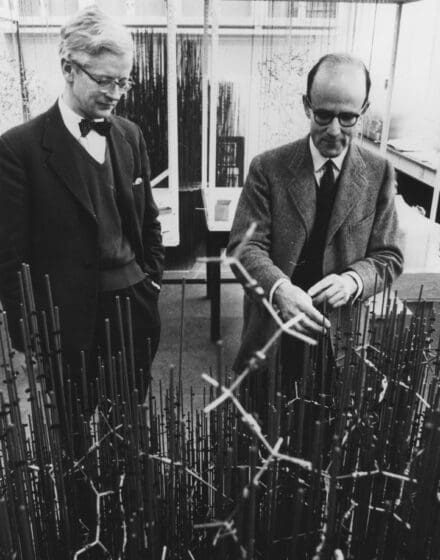 John Kendrew and Max Perutz stood behind a model made of metal rods