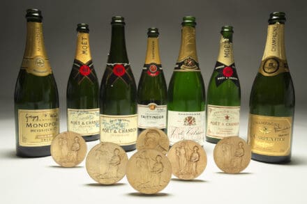 Display of seven Nobel Prize medals in front of champagne bottles signed by winners