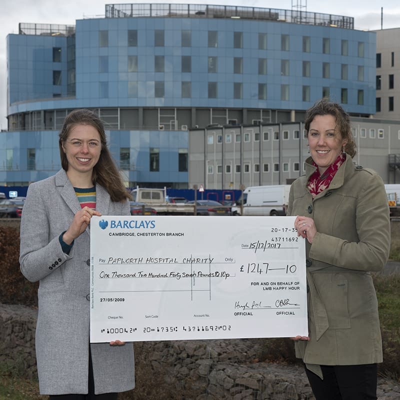 Large cheque held by two women outside the Royal Papworth Hospital building.