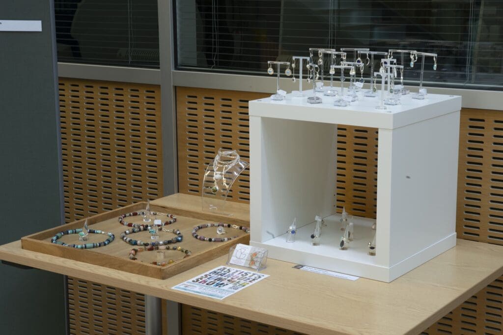 Table and white wooden stand displaying jewellery, including necklaces, earrings, and rings.