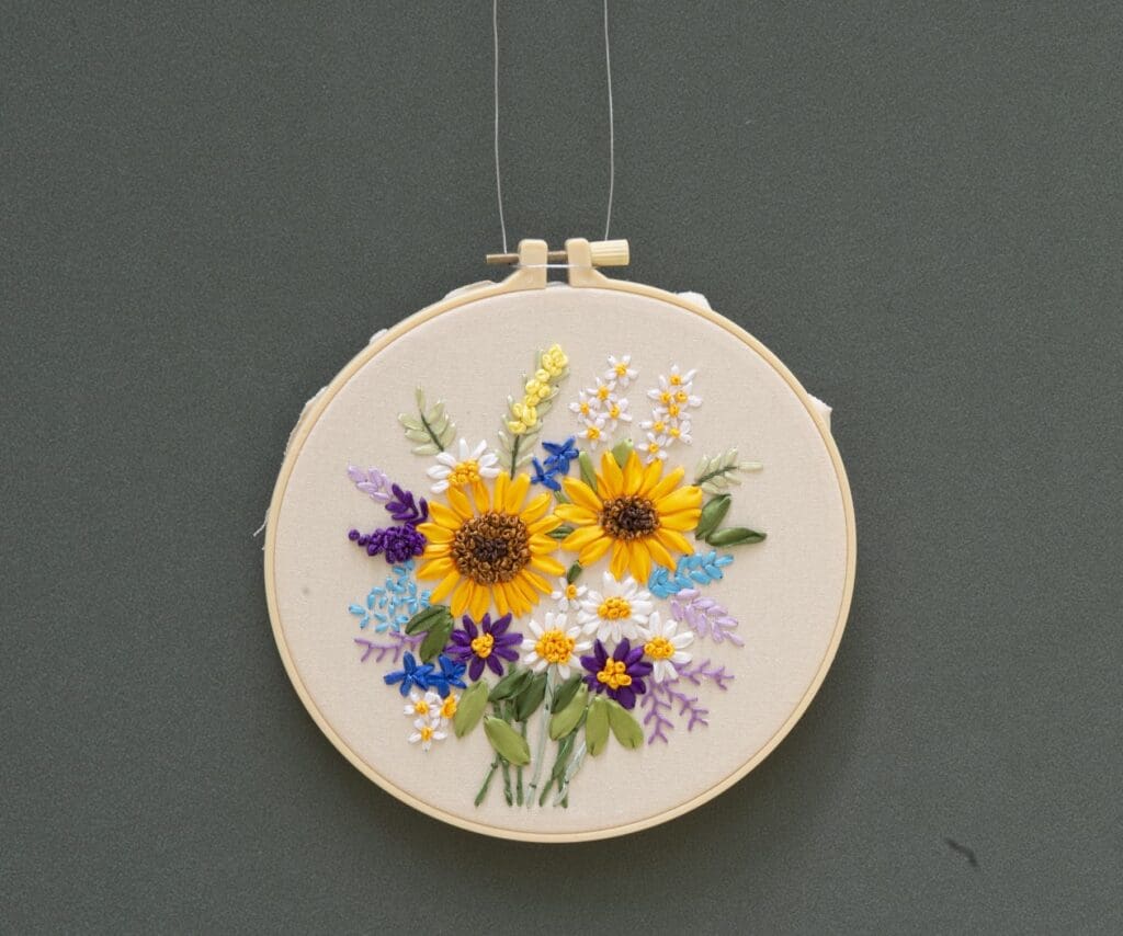 Circular embroidery frame with stitched depiction of a bouquet of flowers.