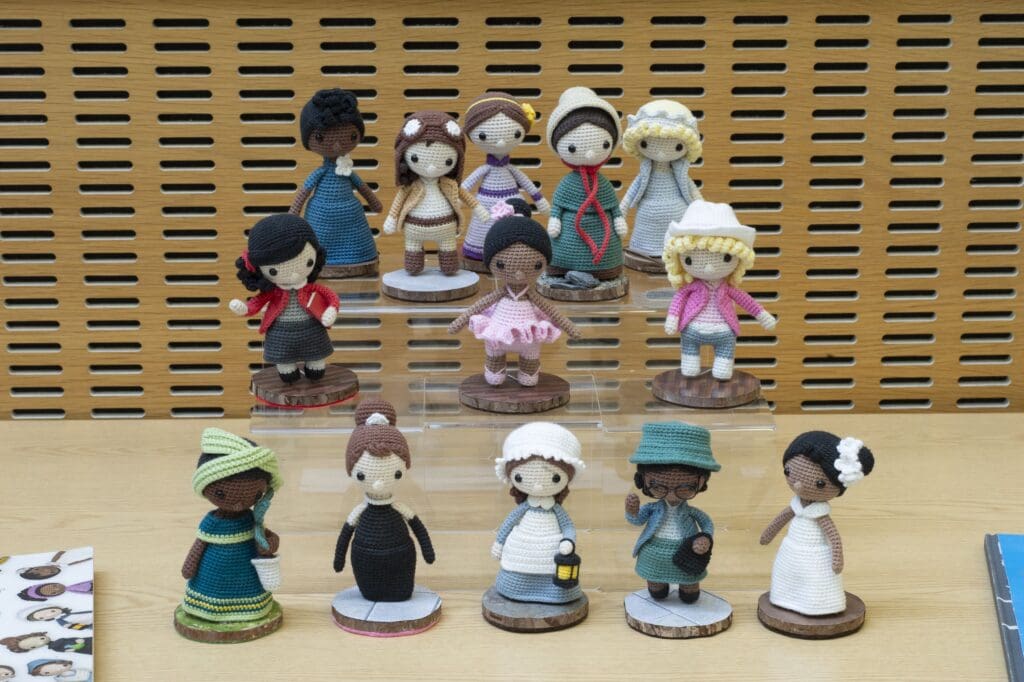 Crocheted female figures displayed on tiered stands.