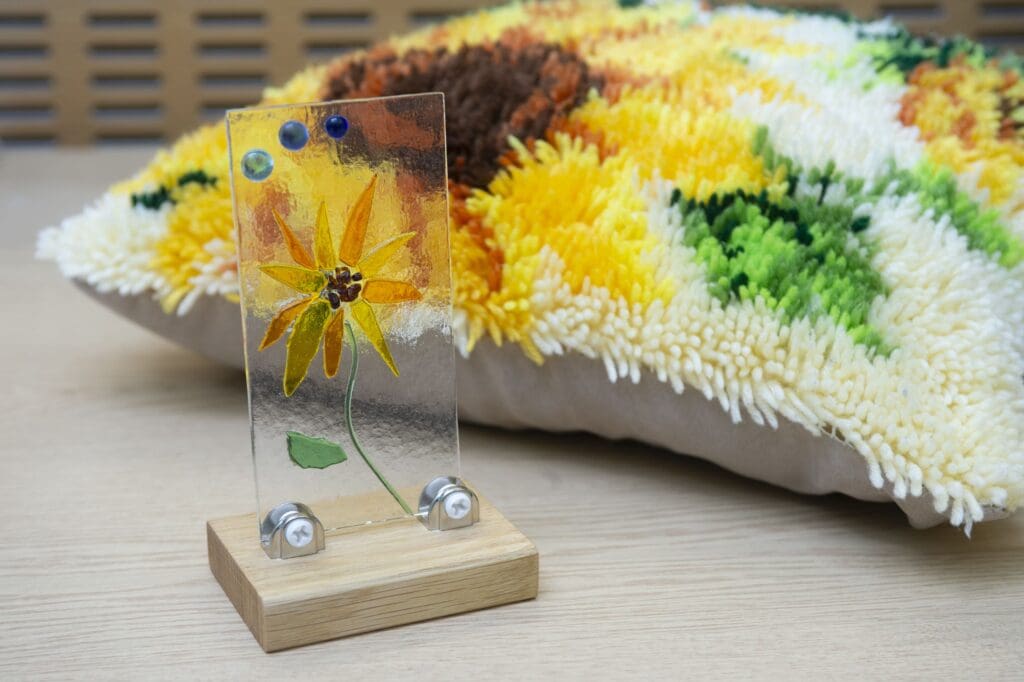 Decorative glasswork and a cushion, both with sunflower designs.