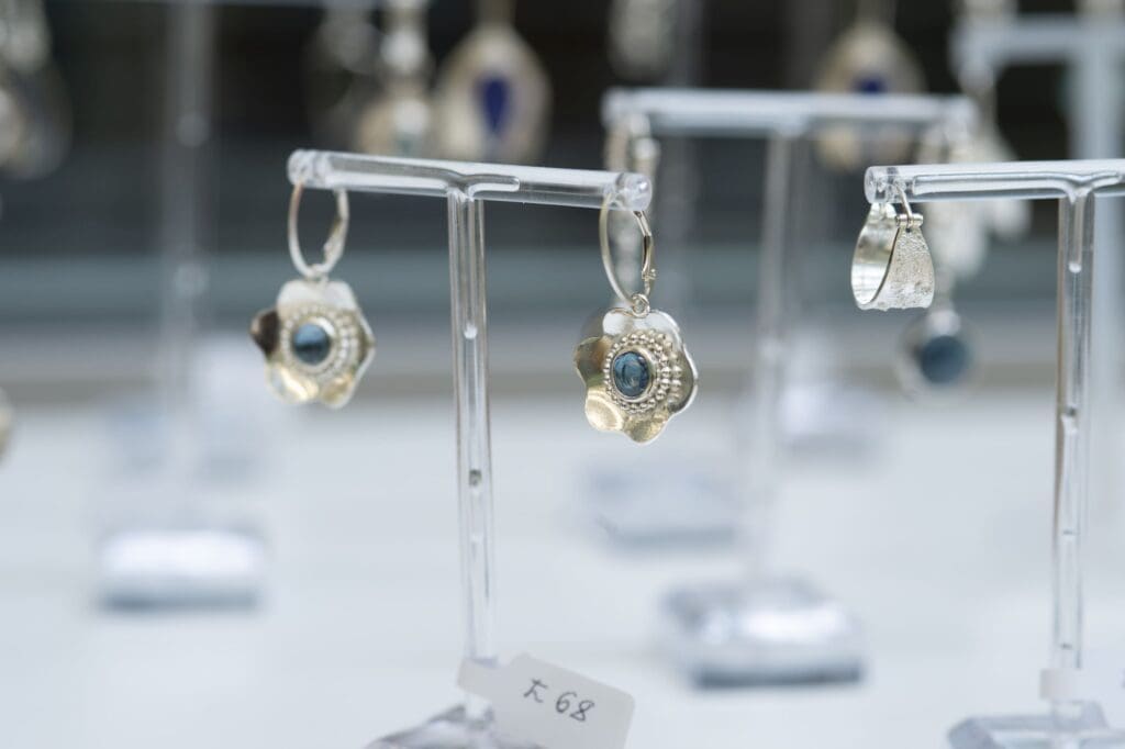 Pair of drop earrings with gemstones displayed on a stand.