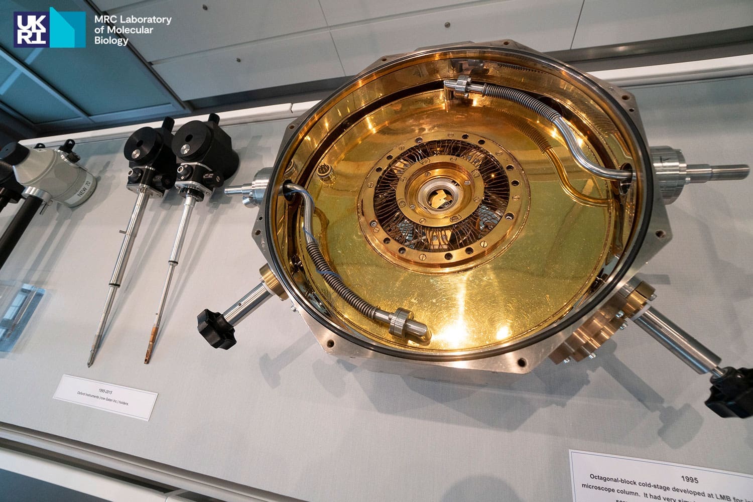 Two pieces of black and silver scientific equipment next to a gold-coloured circular object