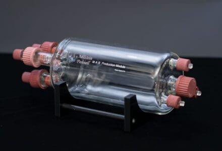 Glass cylindrical chamber with red valves, positioned in a black stand