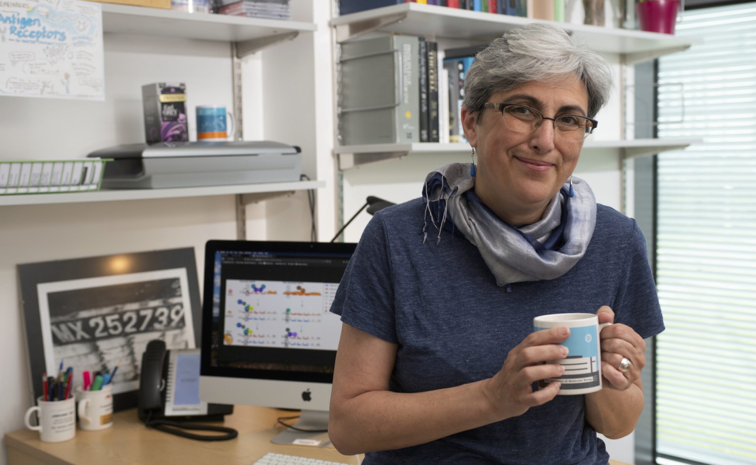 Cristina Rada at a desk holding a mug