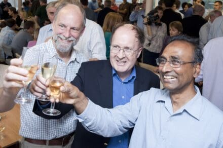 Hugh Pelham, Greg Winter and Venki Ramakrishnan holding champagne glasses aloft