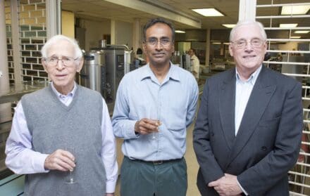 Three scientists in a laboratory setting.