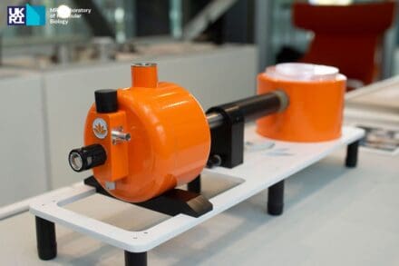 Orange and black scientific equipment mounted on a white and black base