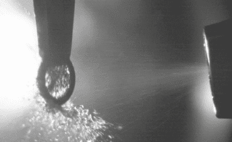 Sprayer nozzle emitting a conical fine mist of liquid droplets, observed through high-speed photography.