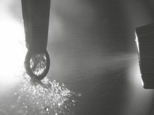 Sprayer nozzle emitting a conical fine mist of liquid droplets, observed through high-speed photography.