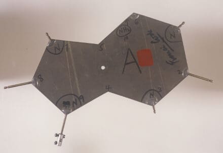 Metal nine-sided shape with various notes written on it in pen.