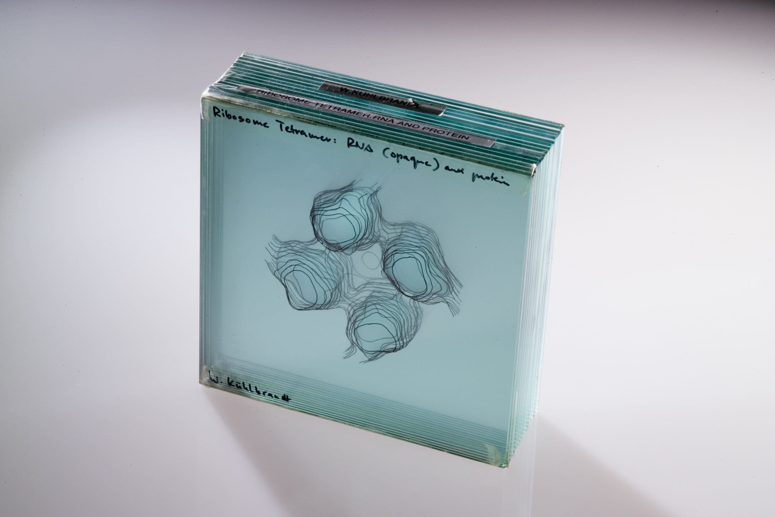 Blue tinted transparent block made of layers which created a structured image.