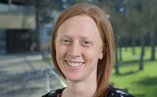 Woman in black floral top looking directly at the camera.