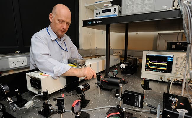 Man adjusting some scientific equipment set out in front of him.