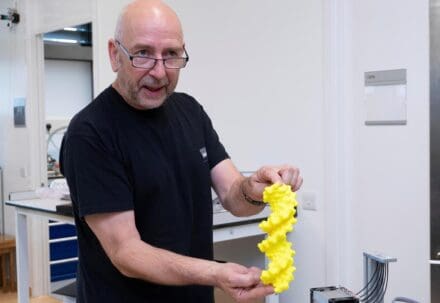 Steve in the LMB workshop, with a 3D printed model of DNA